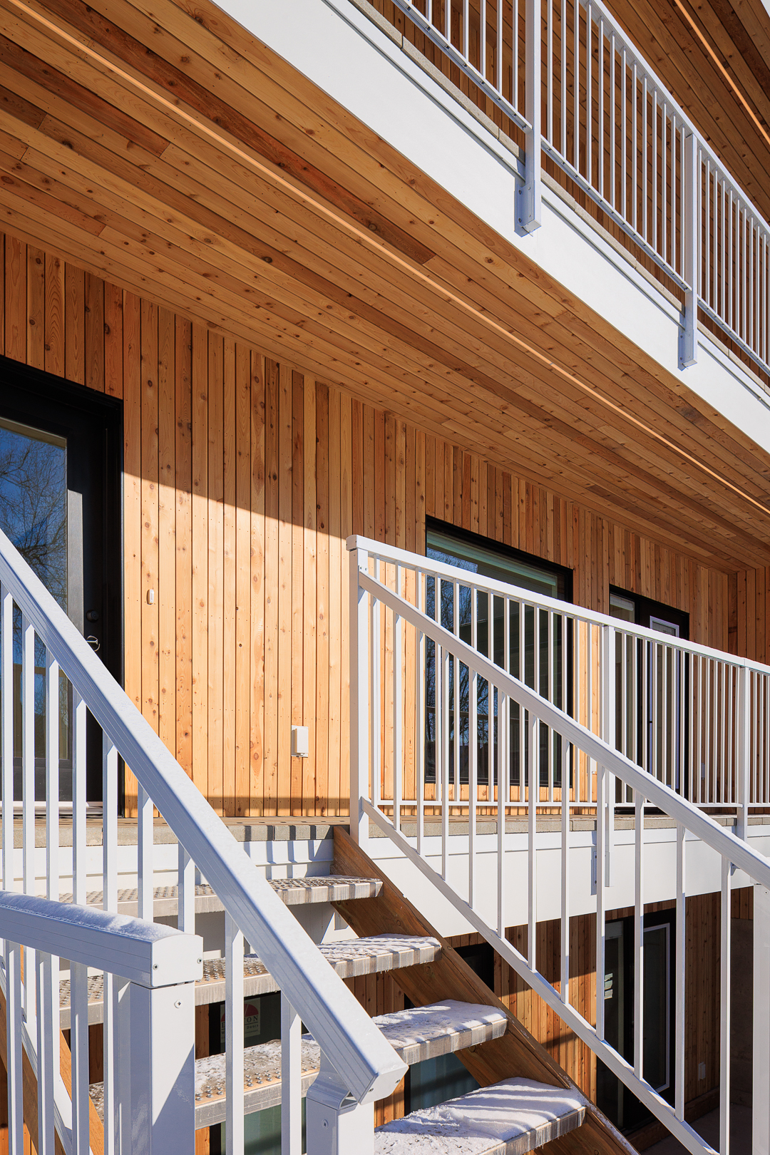 Cedar siding and white stairs leading to the entry